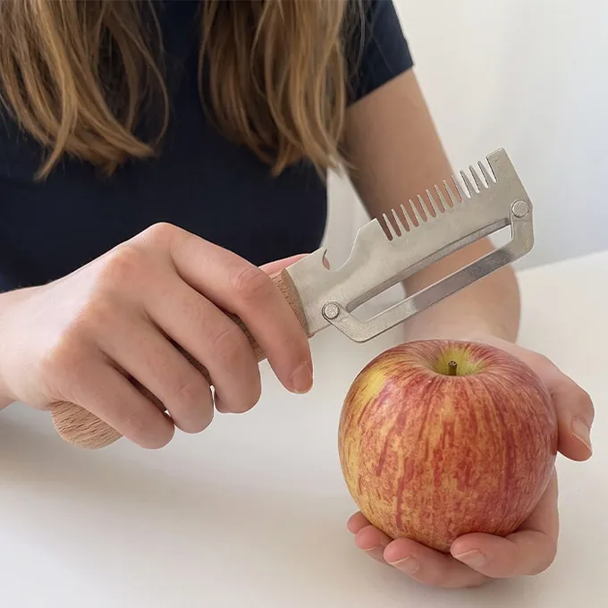 Een vrouw schilt een rode appel met PeelPro